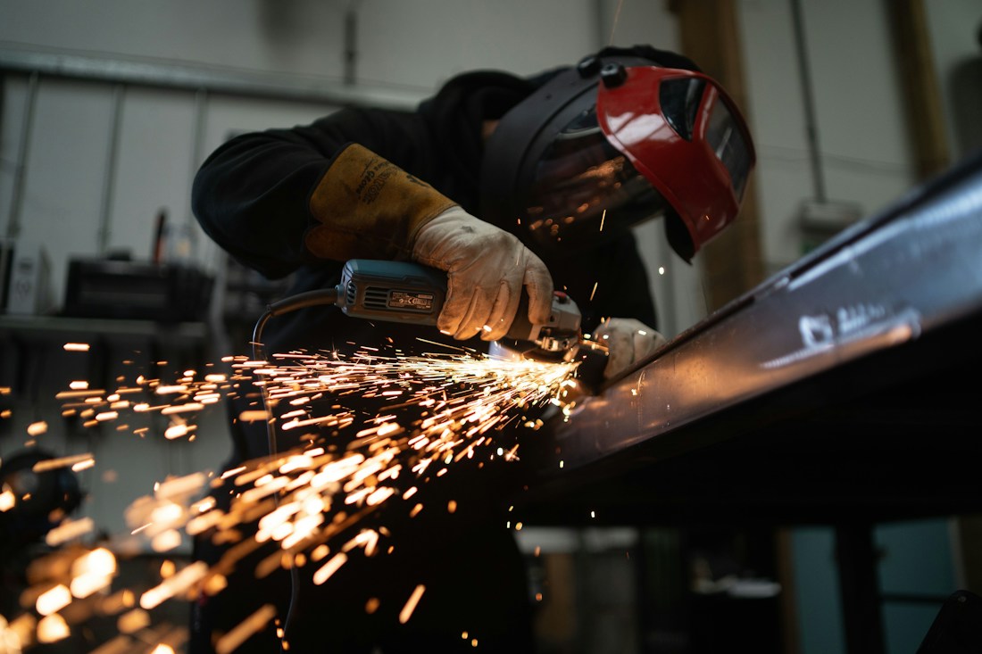 Worker grinding a metal beam with bright sparks
